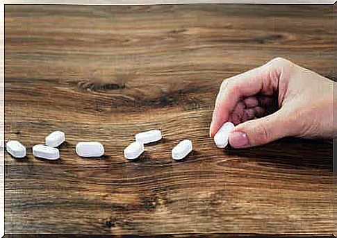 A hand putting a row of pills on the table