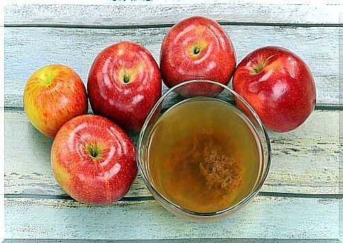 Apple cider vinegar in glass with apples around it